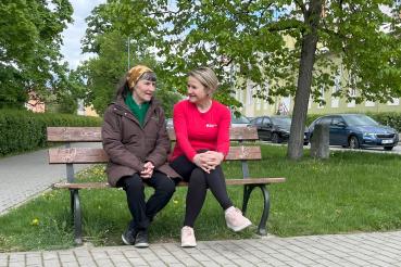 "Doprovodit svého blízkého doma, kde to zná a má to rád, je to nejlepší, co mohou udělat,“ dodává Renata.  Sestřička hovoří se starší ženou na lavičce.